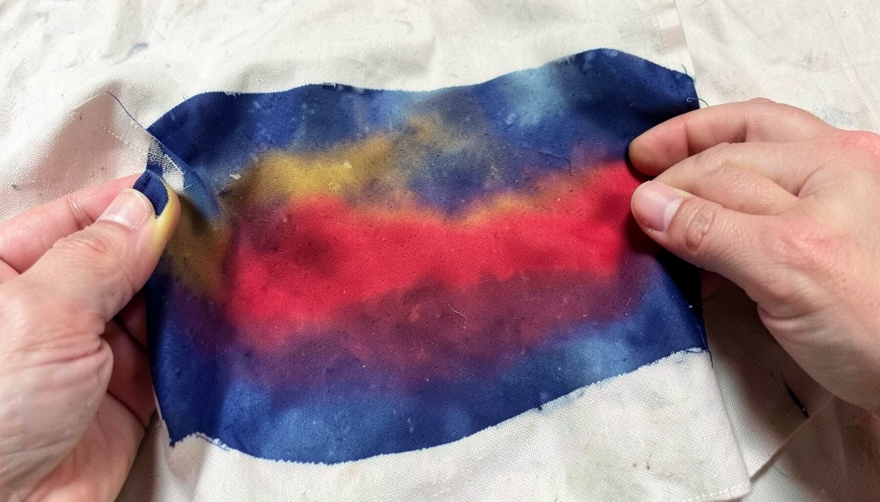 Hands screen-printing fabric with organic pigment, rich indigo and ochre tones on natural cloth